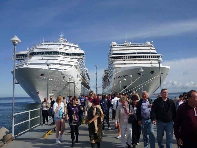 Two cruise ships docked at port with passengers on the pier, first time cruise tips from Barefoot Vacation Travel